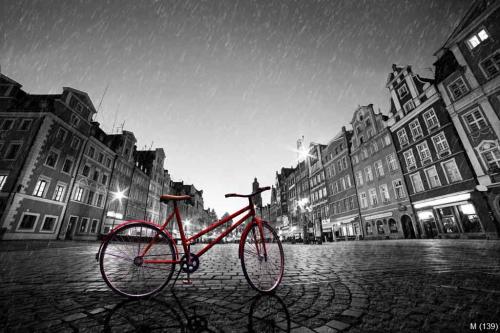Vintage red bike on cobblestone historic old town in rain. Wroclaw, Poland.