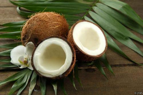 Coconuts with leaves and flower, on grey wooden background