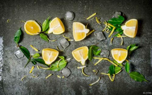 Slices of lemon, ice, leaves on stone table.